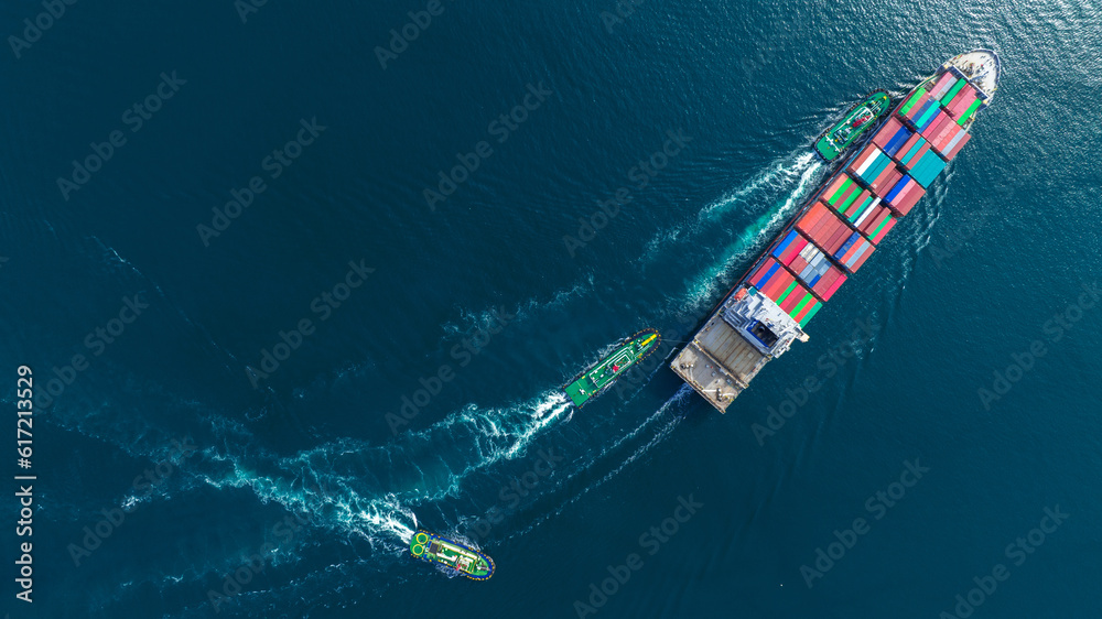 Aerial top view of cargo ship carrying container and running with tug boat for import export goods f