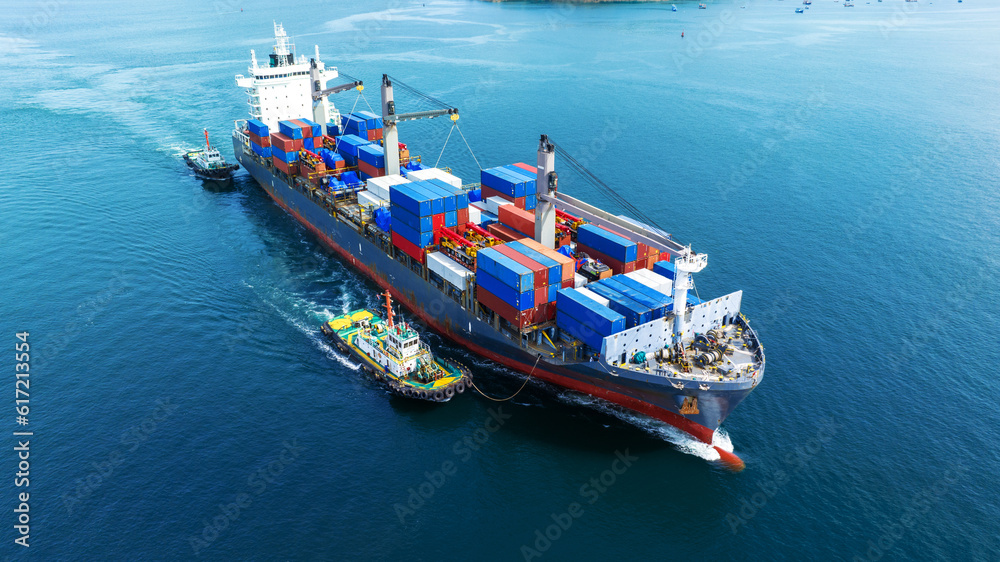 Aerial front view of cargo ship carrying container and running with tug boat for import export goods