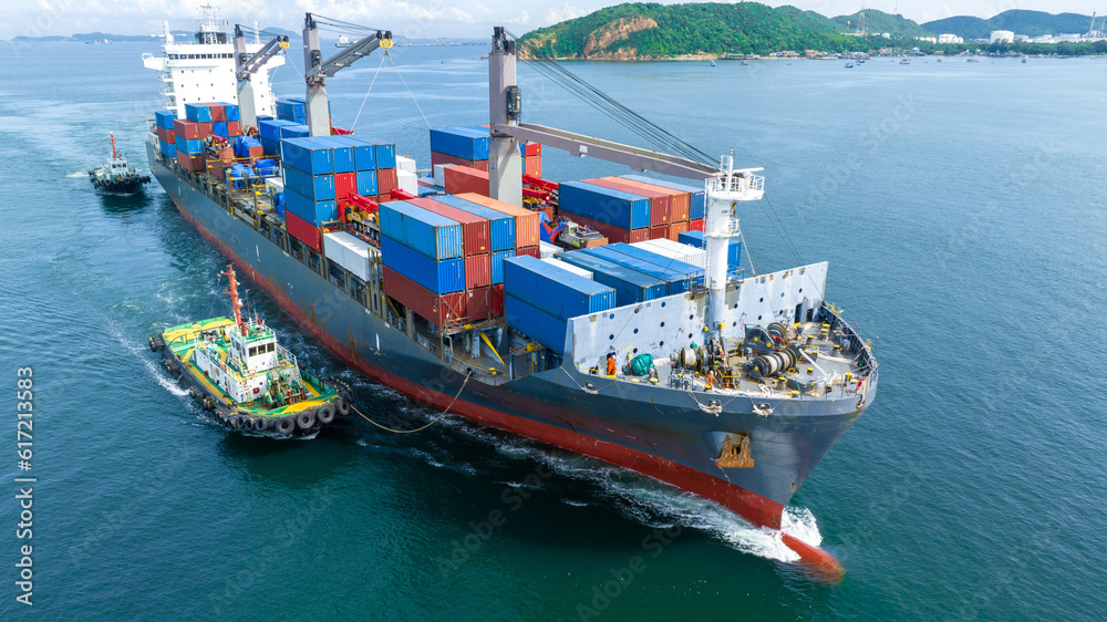 Aerial front view of cargo ship carrying container and running with tug boat for import export goods