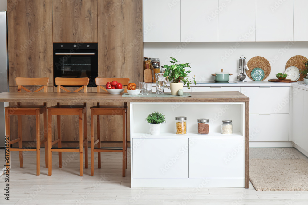 Interior of modern kitchen with island table and white counters