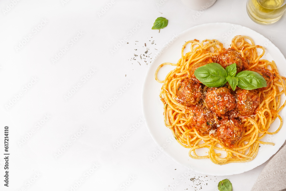 Plate of boiled pasta with tomato sauce and meat balls on white table