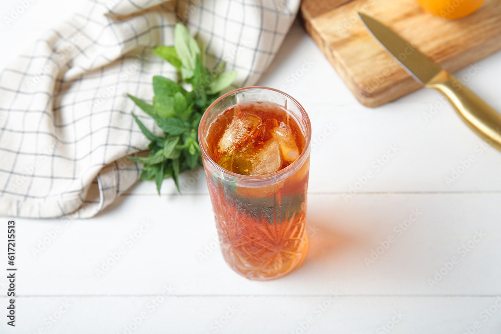 Glass of ice tea with mint on white wooden background