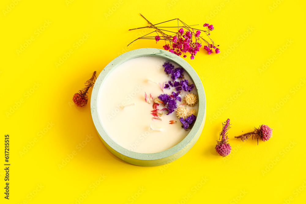 Holder with candle and flowers on yellow background