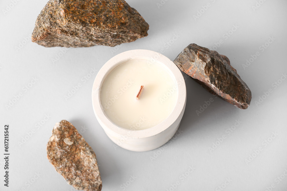 Holder with candle and stones on grey background