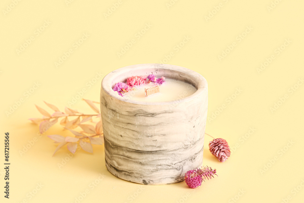 Holder with candle and flowers on beige background