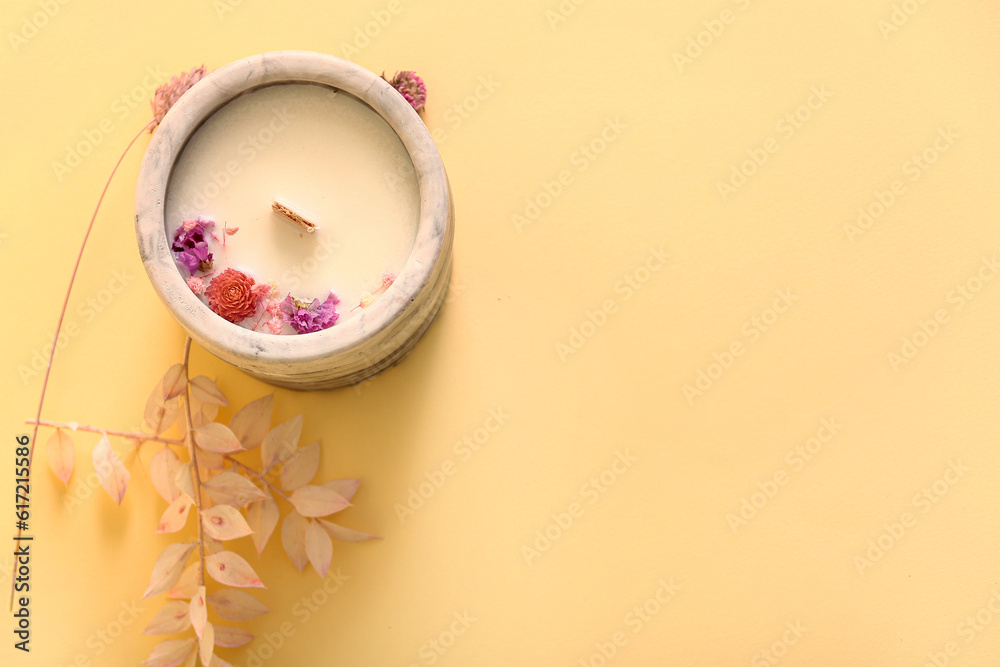 Holder with candle and flowers on beige background