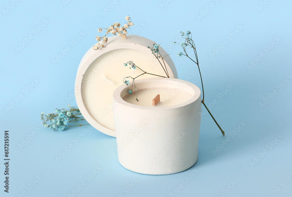 Holders with candles and flowers on blue background