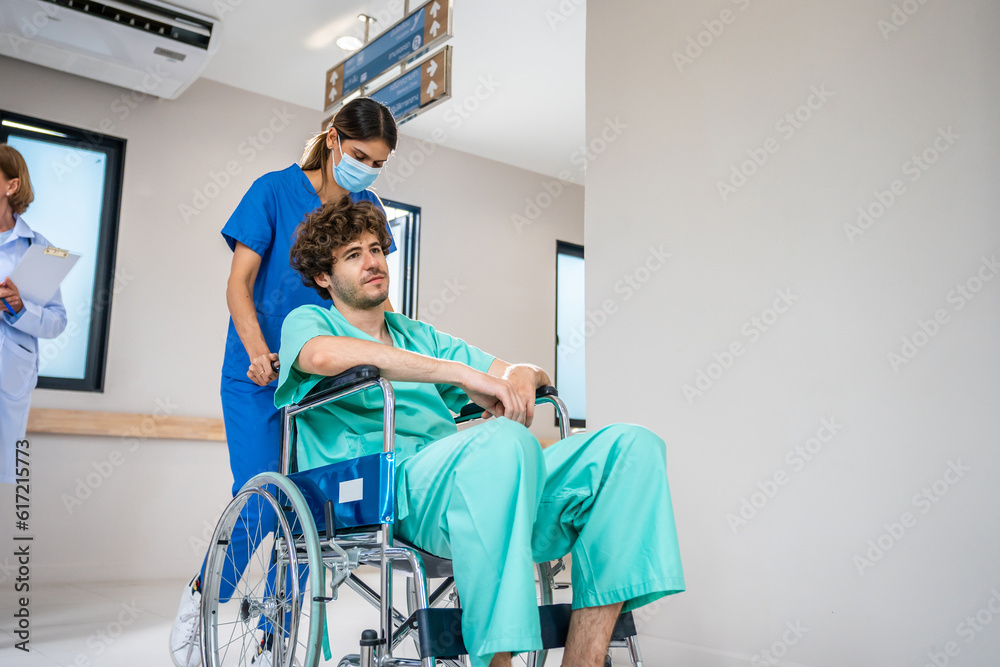 Caucasian doctor support patient sit on wheelchair in hospital hallway. 