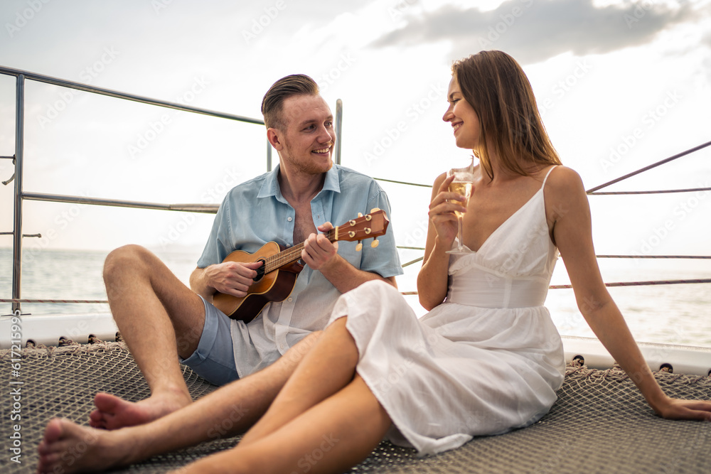 Caucasian romantic couple singing and play ukulele during yachting. 