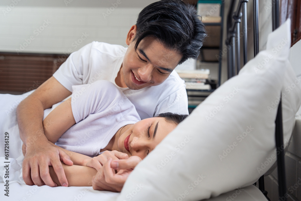 Asian new marriage couple lying down on bed and looking at each other. 