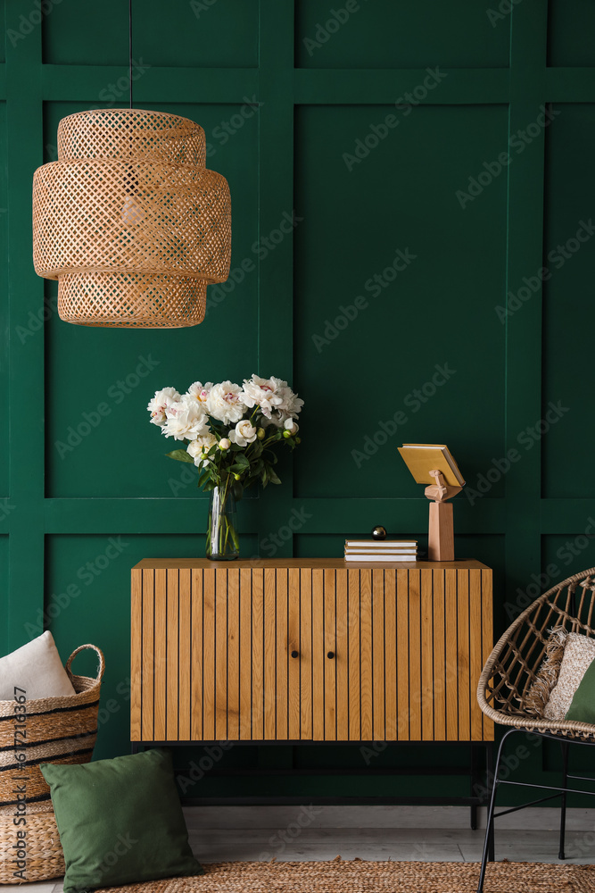 Vase of white peonies with dresser and lamp near green wall