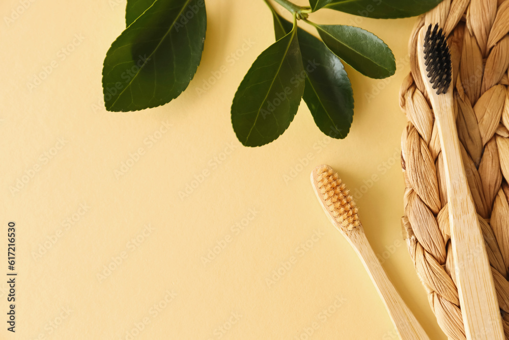 Bamboo tooth brushes and wicker mat on beige background, top view