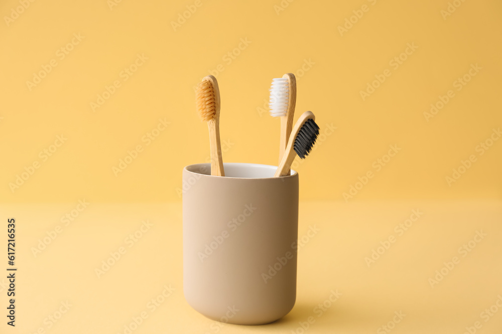 Bamboo tooth brushes in holder on beige background