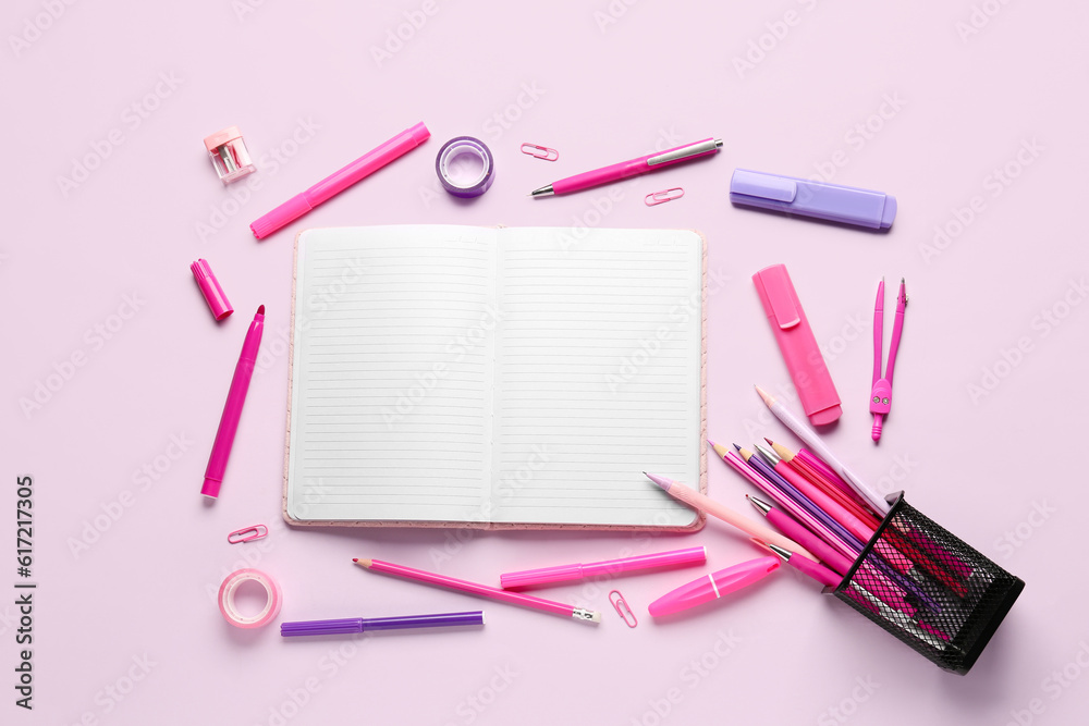 Notebook with different school stationery on lilac background