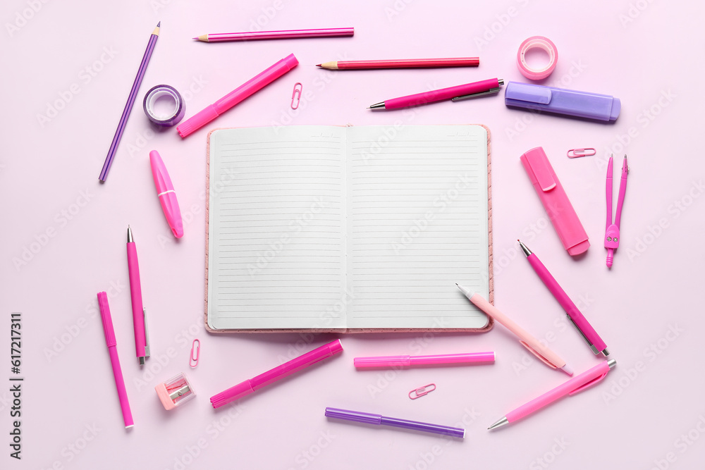 Notebook with different school stationery on lilac background