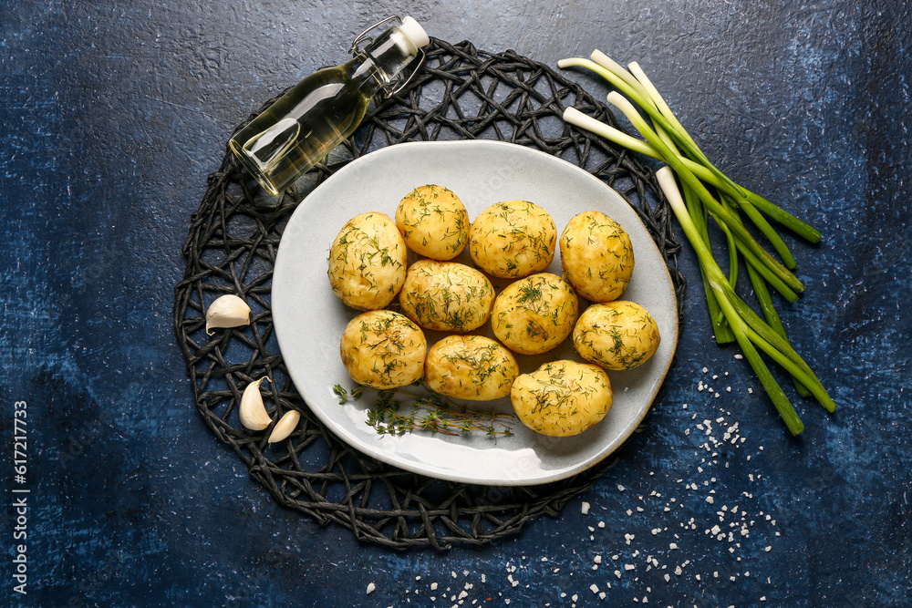 Plate of boiled baby potatoes with dill and green onion on blue background