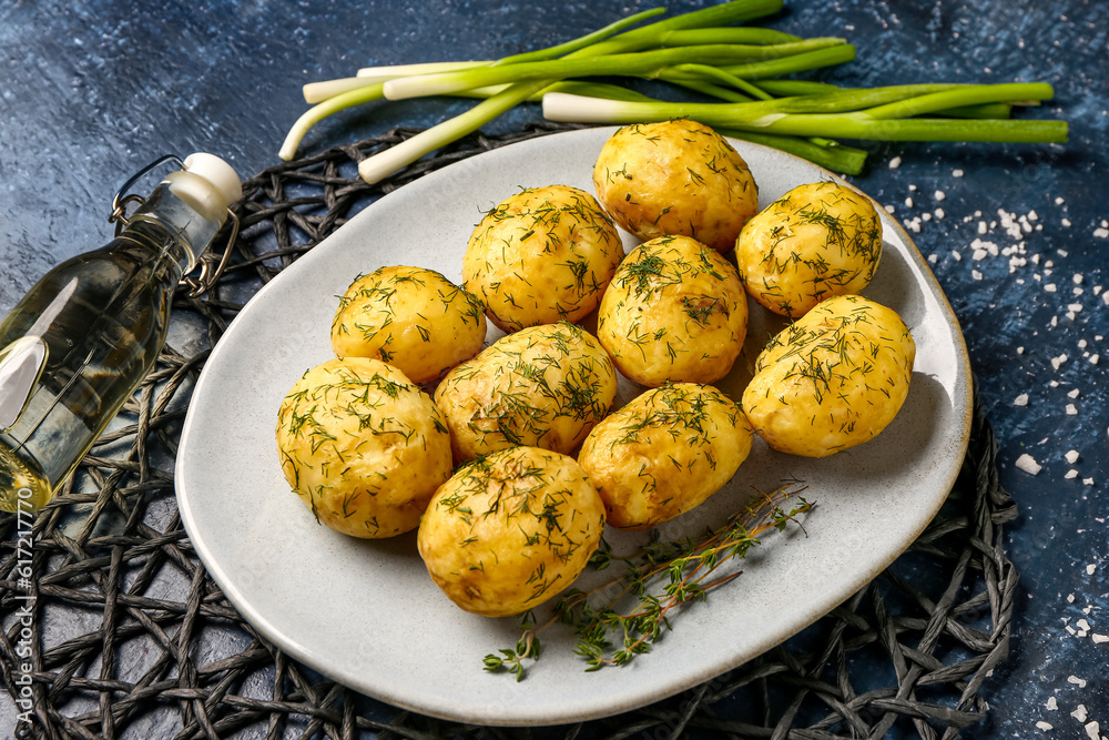 Plate of boiled baby potatoes with dill and green onion on blue background