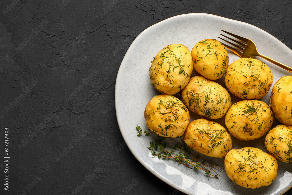 Plate of boiled baby potatoes with dill on black background