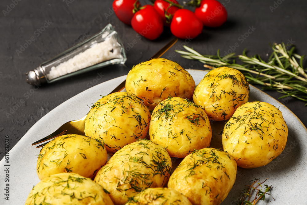 Plate of boiled baby potatoes with dill and rosemary on black background