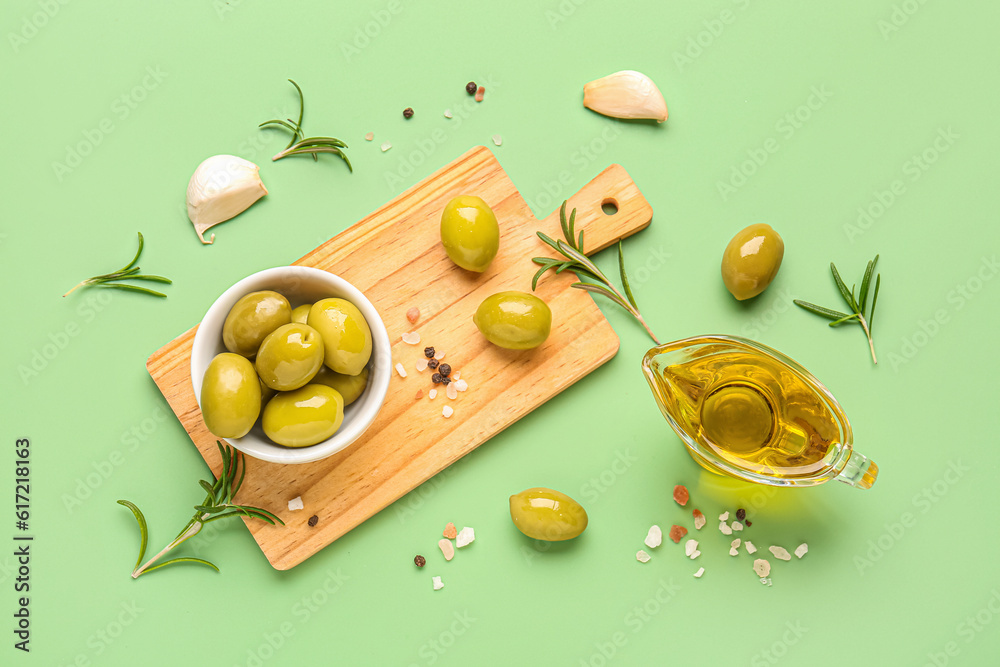 Bowl with ripe olives and gravy boat of oil on green background