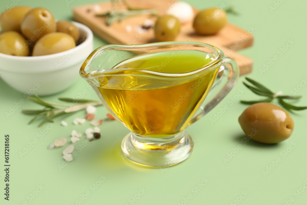 Gravy boat of fresh olive oil on green background