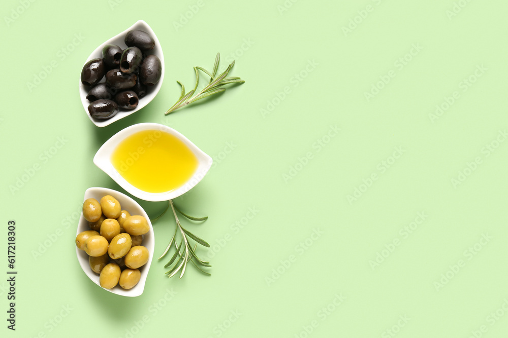 Bowls with ripe olives and oil on green background