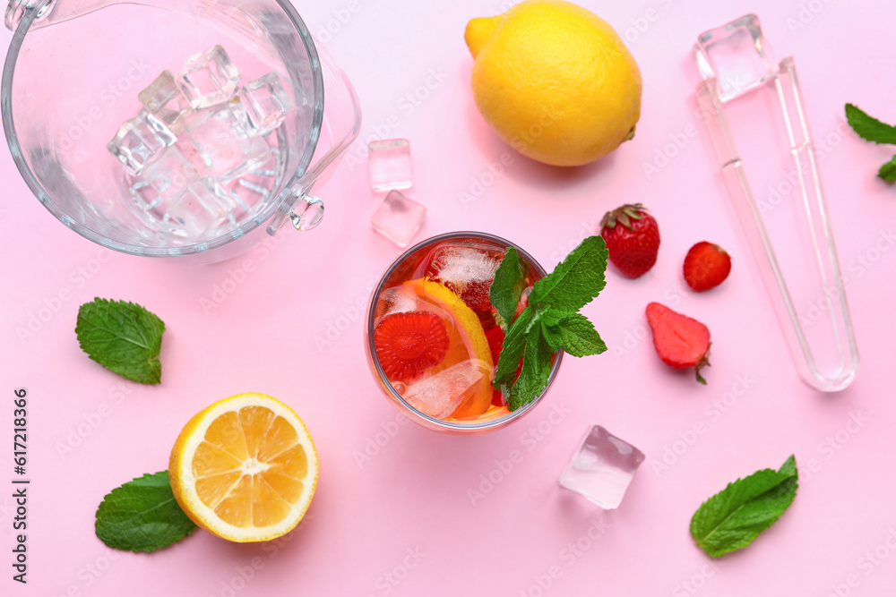 Glass of infused water with strawberry and lemon on pink background