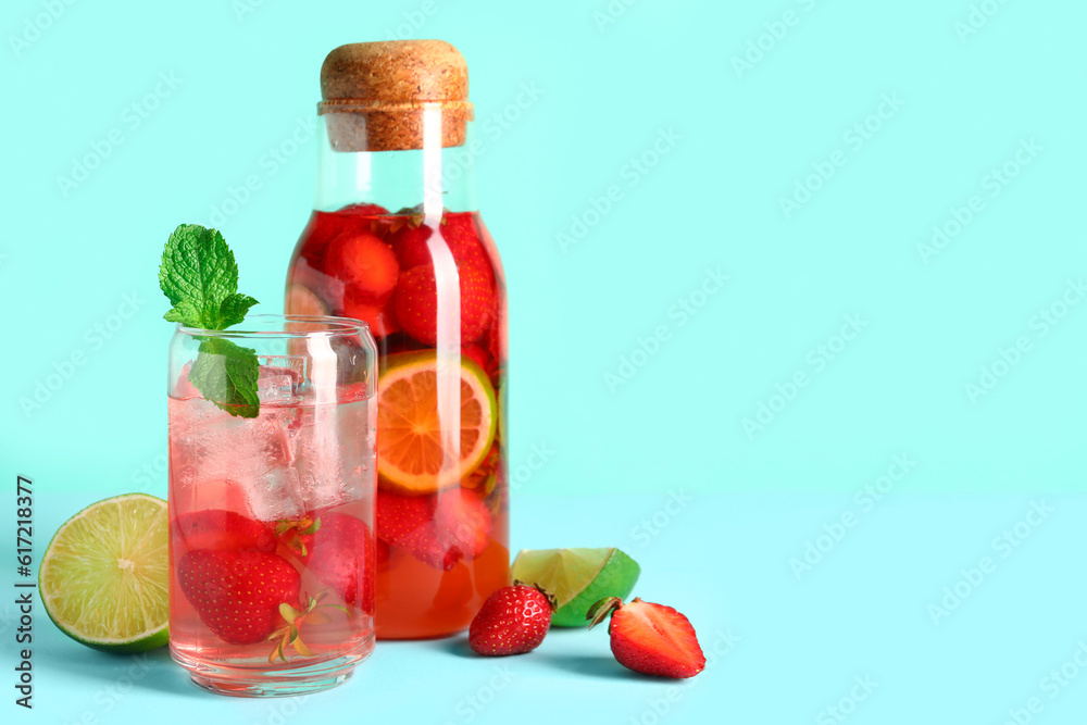 Glass and bottle of infused water with strawberry on blue background