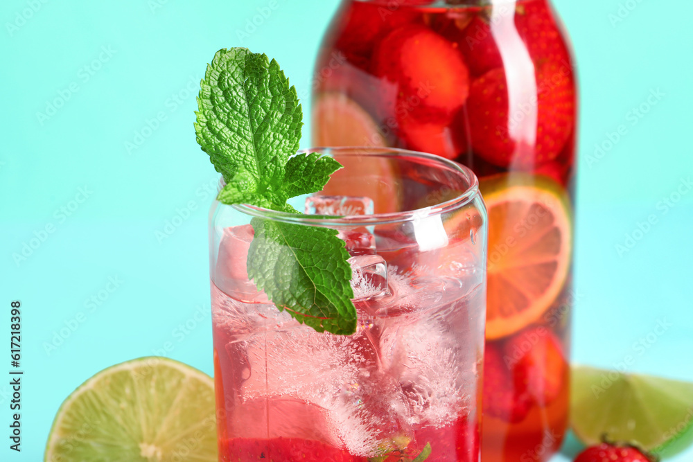 Glass and bottle of infused water with strawberry on blue background