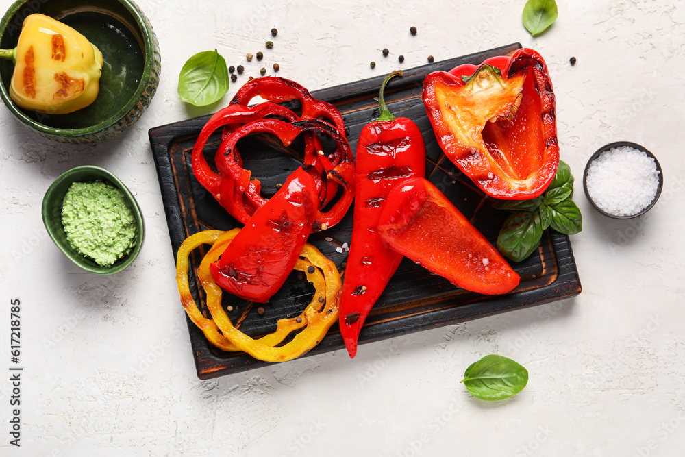 Wooden board with tasty grilled peppers on light background