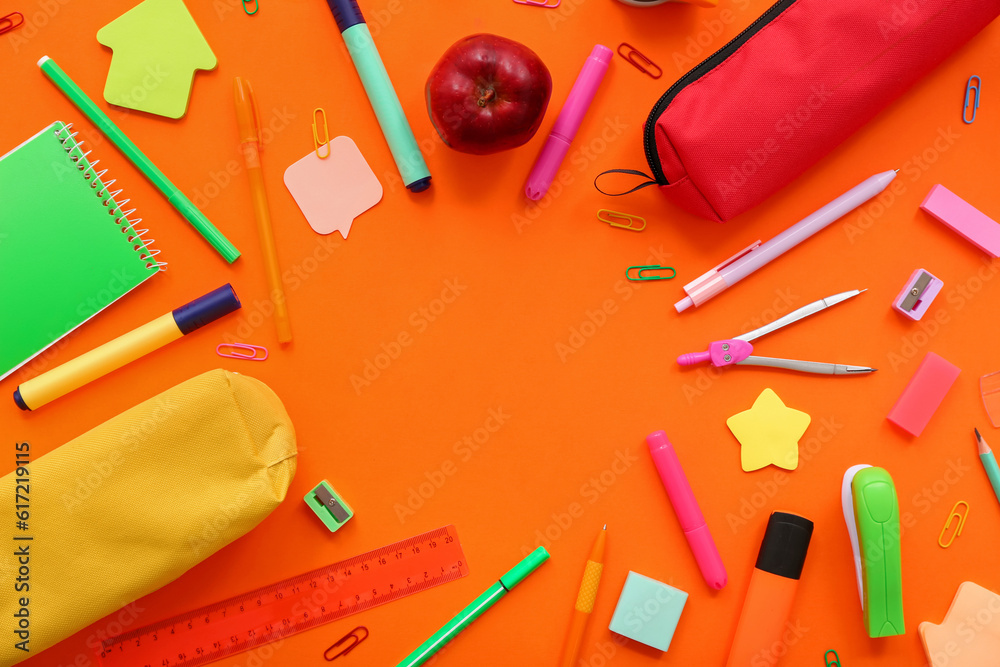 Frame made of fresh apple and different stationery on orange background