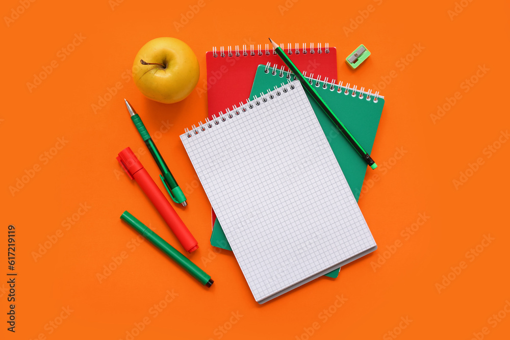 Fresh apple with different stationery on orange background