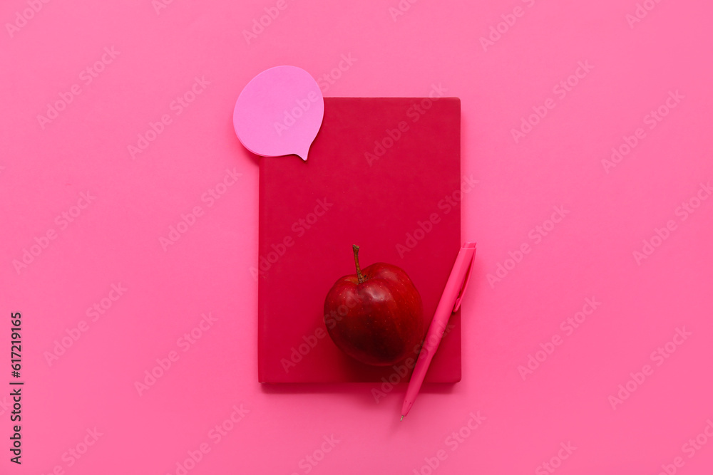 Notebook with fresh red apple, pen and bubble speech on pink background