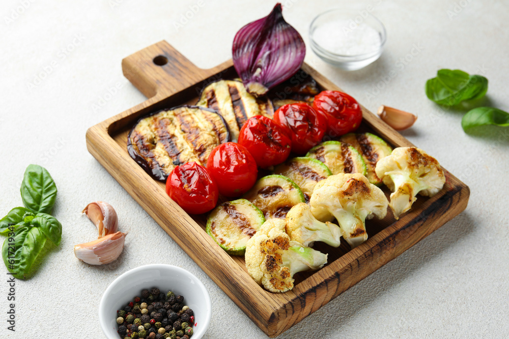 Wooden board with grilled vegetables on white background