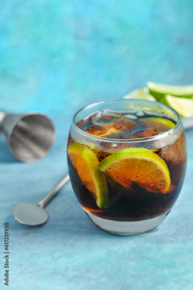 Glass of cold Cuba Libre cocktail on blue background