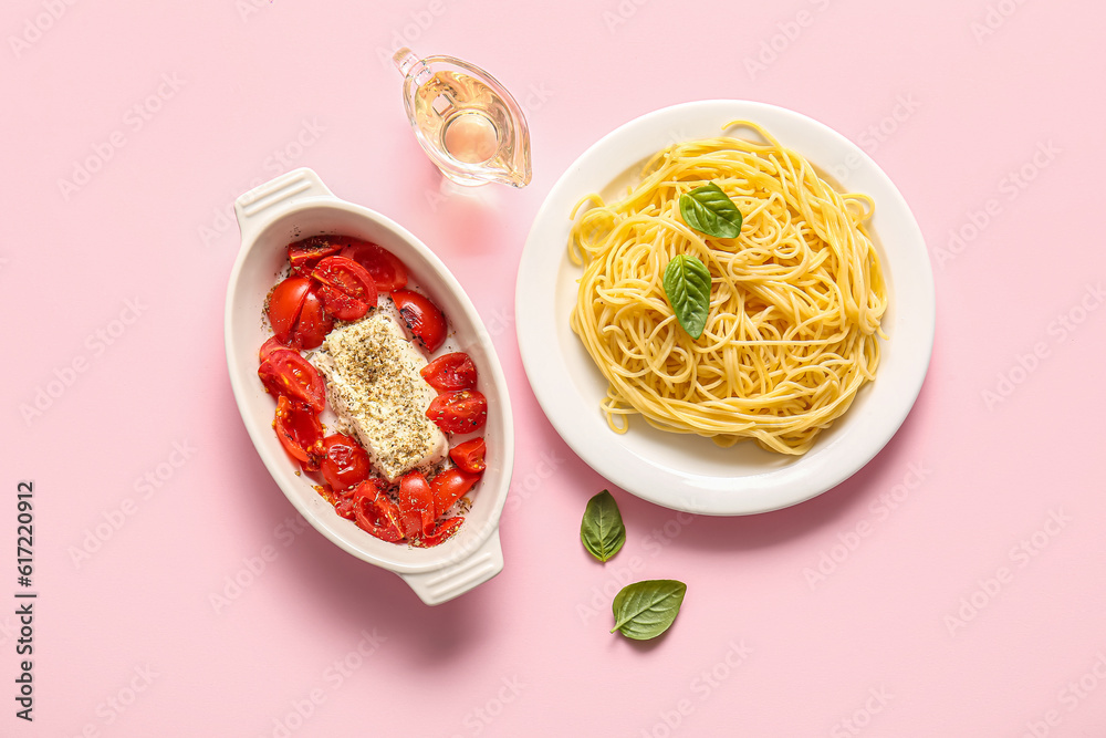 Baking dish with tasty tomatoes, feta cheese and pasta on pink background