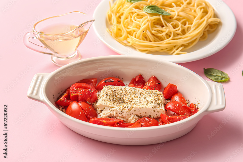 Baking dish with tasty tomatoes and feta cheese on pink background