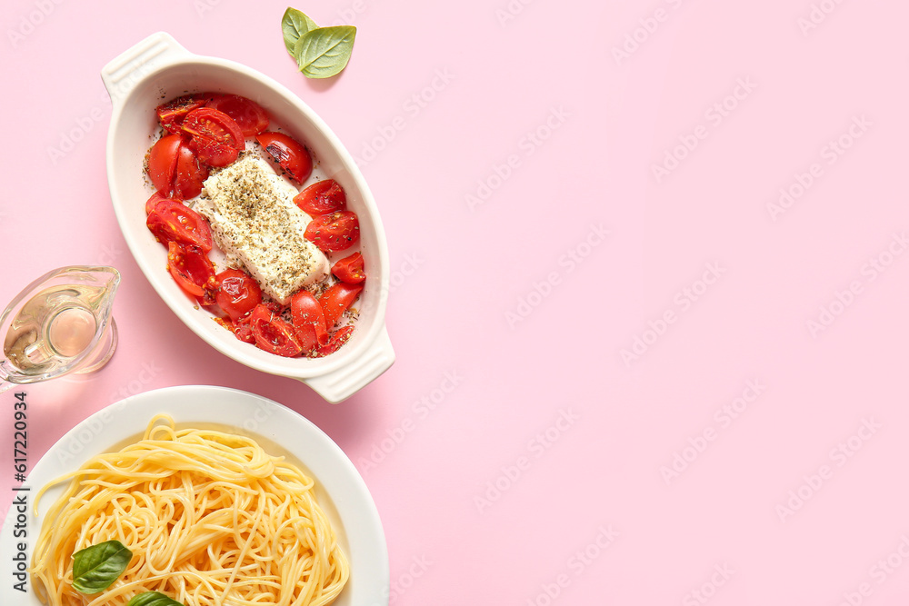 Baking dish with tasty tomatoes, feta cheese and pasta on pink background