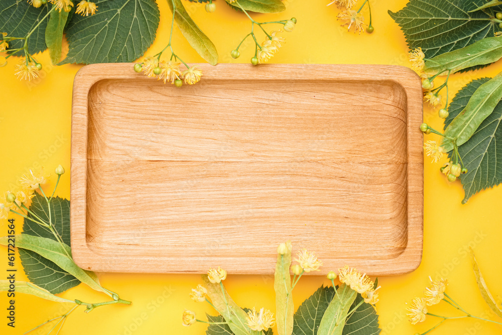 Composition with wooden board and fresh linden flowers on yellow background