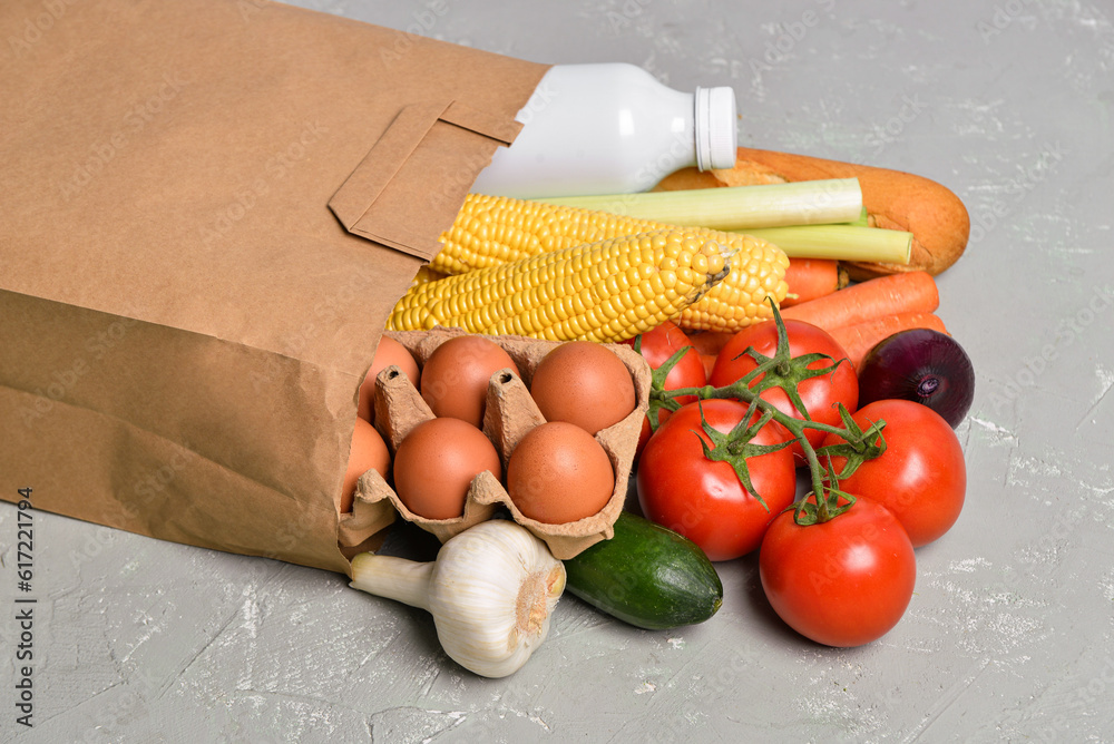 Paper bag with different products on grey background