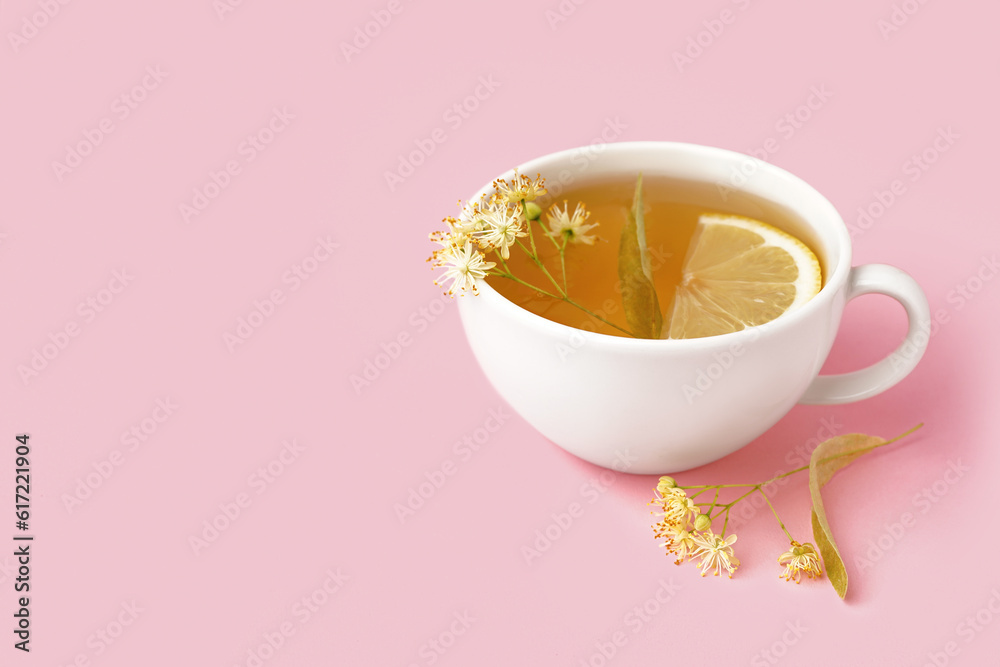 Cup of linden tea with lemon on pink background