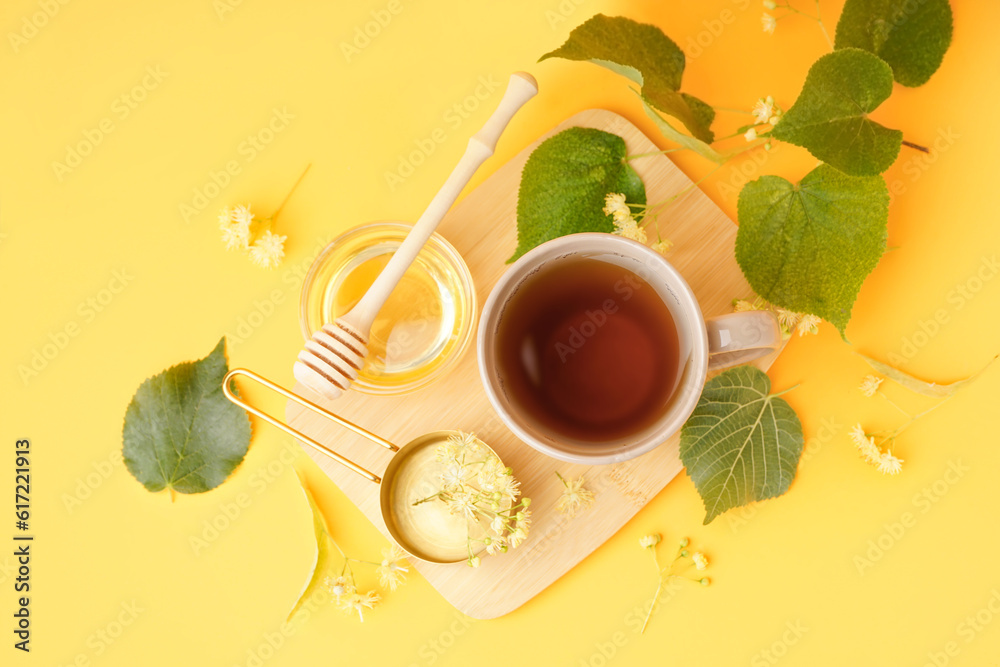 Cup of linden tea and bowl with honey on orange background