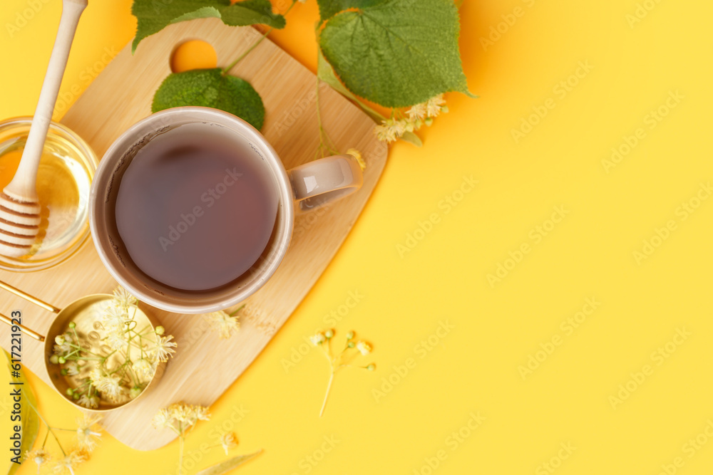 Cup of linden tea and bowl with honey on orange background