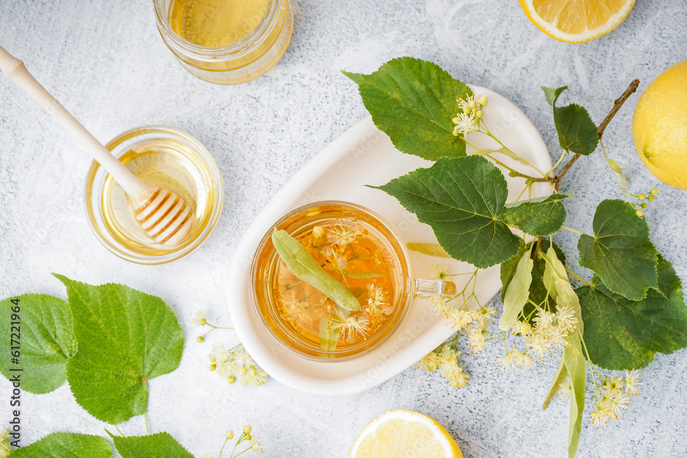 Glass cup of linden tea and bowl with honey on white background