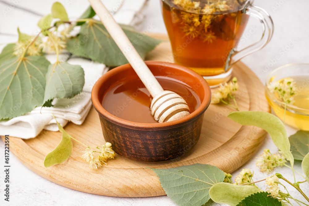 Bowl with linden honey and glass cup of tea on white background