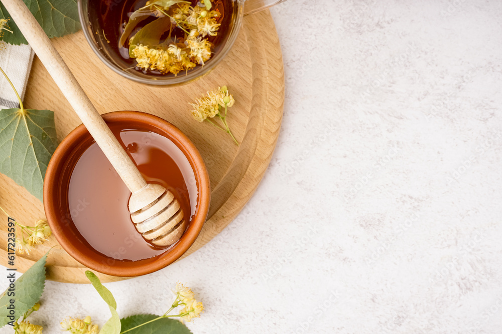 Bowl with linden honey and glass cup of tea on white background