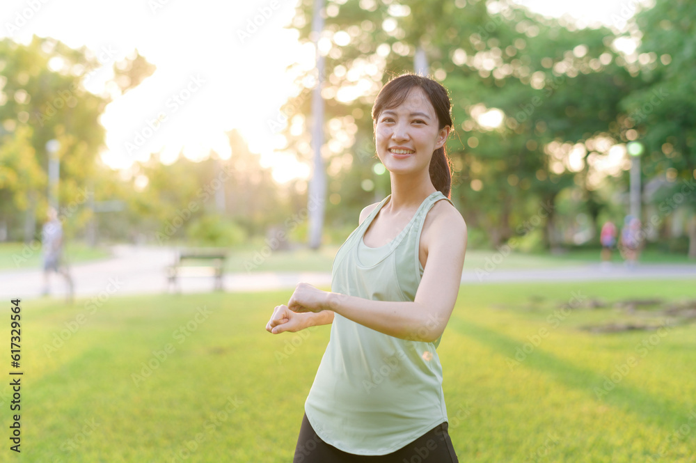 Female jogger. Fit young Asian woman with green sportswear stretching muscle in park before running 