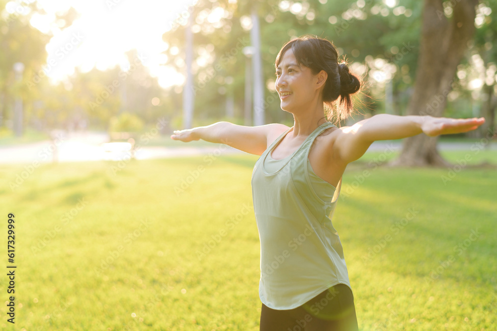 Female jogger. Fit young Asian woman with green sportswear stretching muscle in park before running 