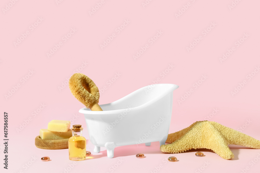 Small bathtub, bath supplies and starfish on pink background