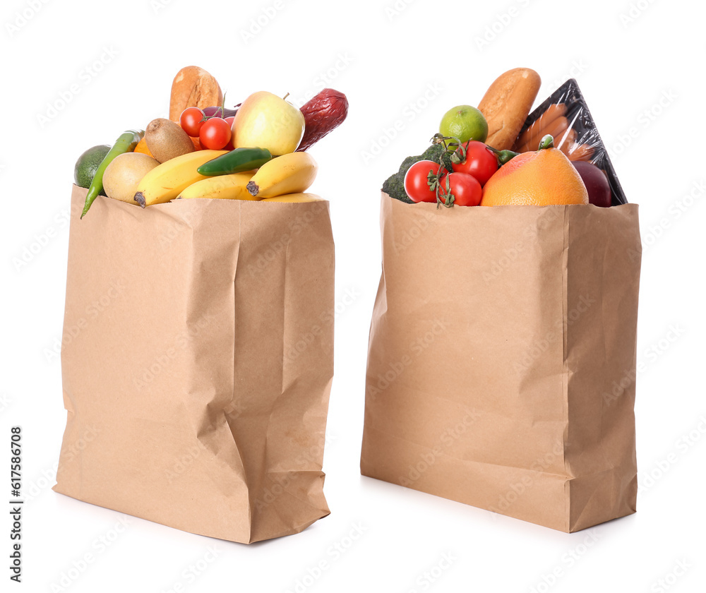 Paper bags with vegetables, fruits and sausages on white background